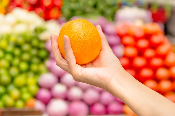 Frau hält Orange im Supermarkt — Stockfoto