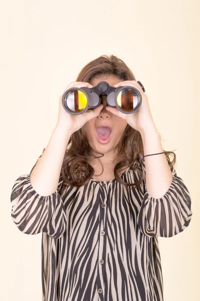 Mujer linda sosteniendo binoculares, fondo amarillo — Foto de Stock