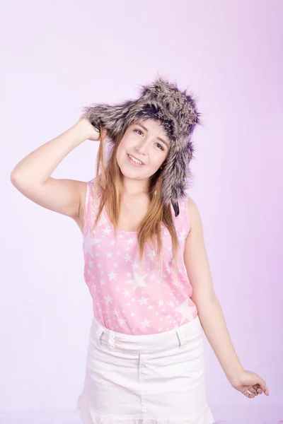 Hapy meisje in bont cap en roze achtergrond — Stockfoto