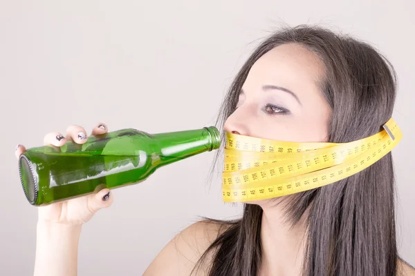 Woman has tape measure around her mouth with beer — Stock Photo, Image