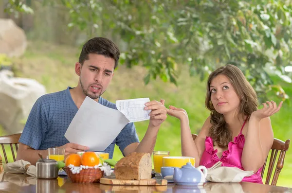 Couple prenant le petit déjeuner se battant sur les factures à la maison avec jardin en arrière-plan — Photo
