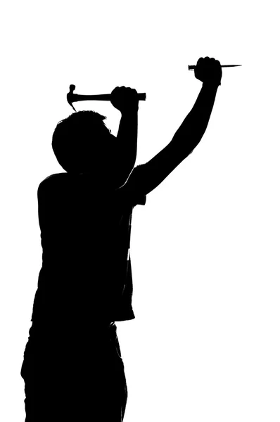 Silhueta de um homem com um martelo e prego . — Fotografia de Stock