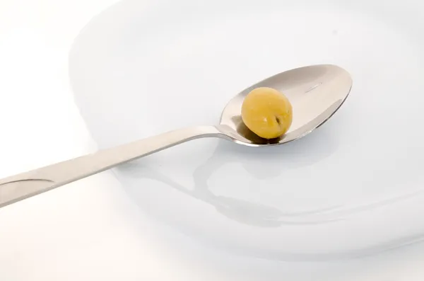 Cucchiaio con oliva su sfondo bianco — Foto Stock