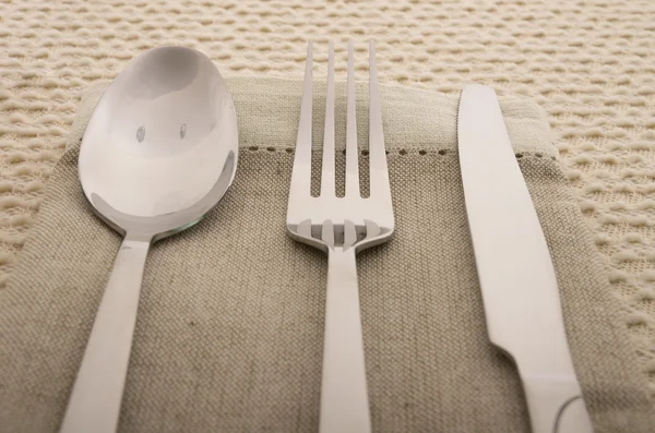 Kniv, gaffel och sked med linne servett — Stockfoto