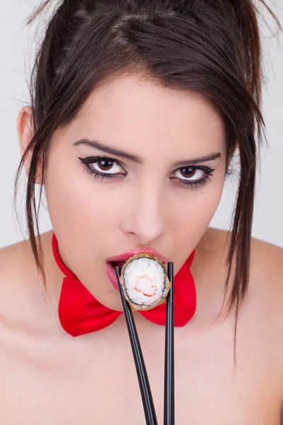 Beautiful young woman eating sushi roll — Stock Photo, Image