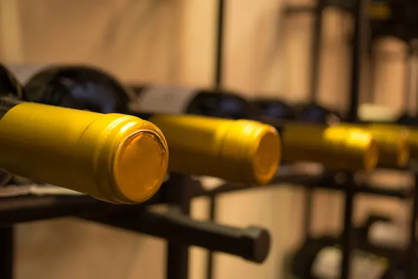 Бутылки вина, сложенные на стойках, снятые с ограниченной глубиной резкости — стоковое фото