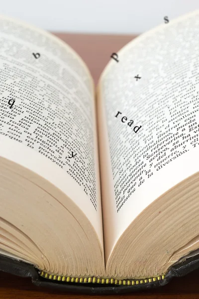 Old open book with magic falling letters on wood — Stock Photo, Image