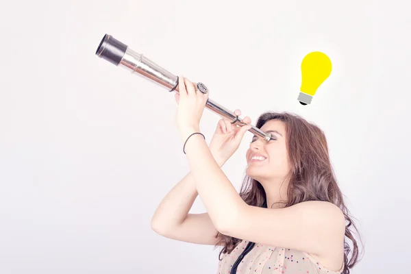 Młoda kobieta myśleć żarówki za pomocą teleskopu — Zdjęcie stockowe