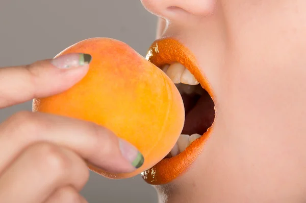 Vacker ung kvinna äter en persika. — Stockfoto