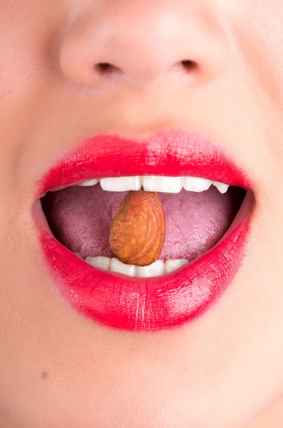 Primer plano de boca femenina comiendo almendras — Foto de Stock