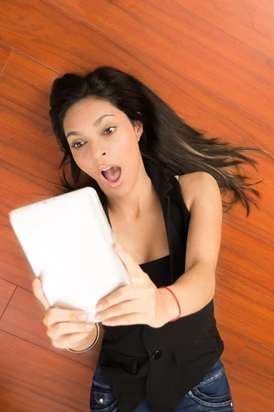 Szczęśliwa młoda kobieta leżący przy użyciu komputera typu tablet pc w domu — Zdjęcie stockowe
