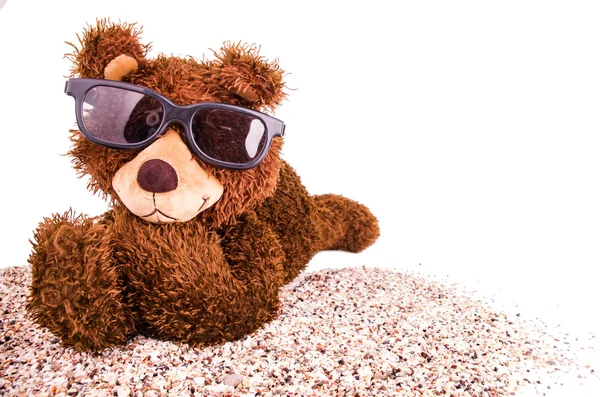 Urso de pelúcia com óculos de sol na areia — Fotografia de Stock