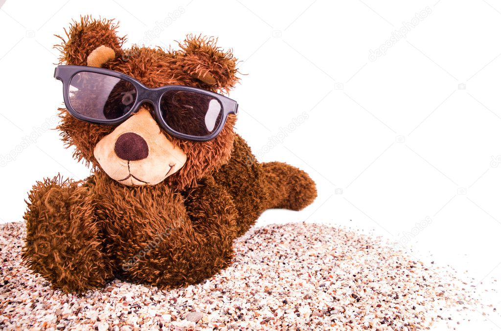 Teddy bear with sunglasses on the sand