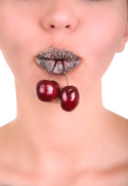 Beautiful girl's lower part of face with two red cherries in mouth