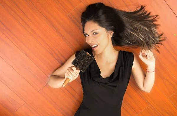 Happy attractive woman singing to comb on the floor — Stock Photo, Image