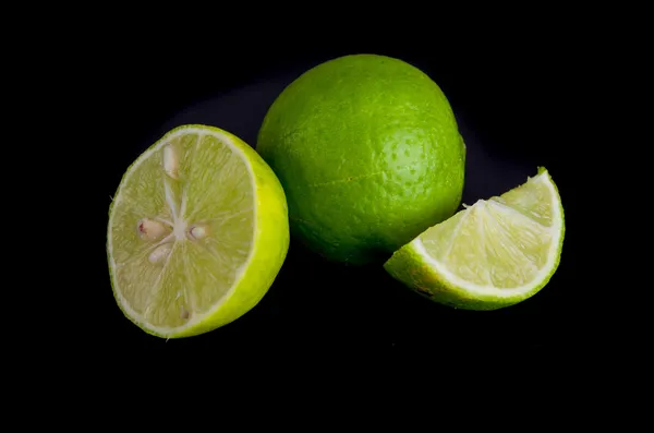 Citrus kalk fruit helft op zwarte achtergrond, kleine groene citroenen — Stockfoto