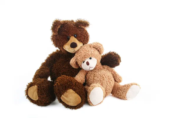 Two teddy bears, bigger and smaller, sitting close to each other like they are best friends. — Stock Photo, Image