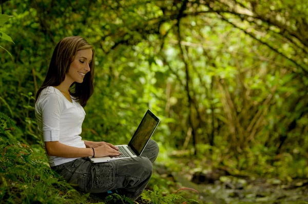 Vrouw in het bos met behulp van een laptop — Stockfoto