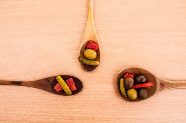 Holzlöffel und Gemüse und Oliven auf einem Holzbrett — Stockfoto