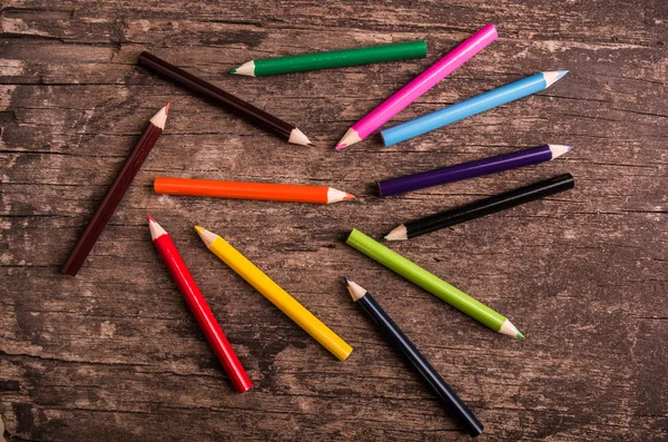 Färgpennor utspridda på trä bakgrund — Stockfoto