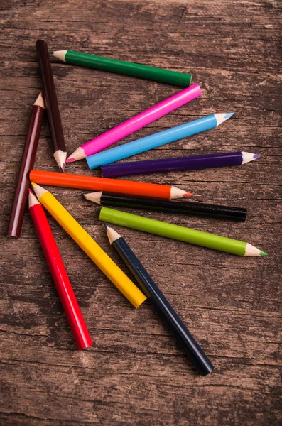 Color pencils scattered on wood background — Stock Photo, Image