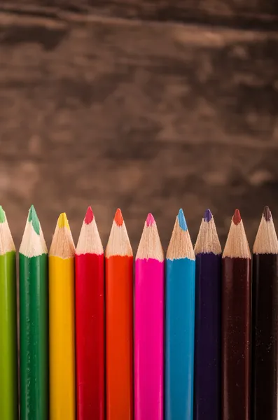 Kleur potloden verspreid over hout achtergrond — Stockfoto