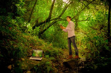 orman içinde laptop ile tablet kullanan adam