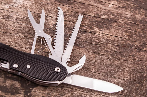 Black swiss army knife on wood color toned — Stock Photo, Image