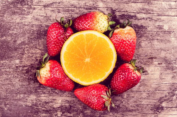 Erdbeeren und Orangen auf Holz — Stockfoto