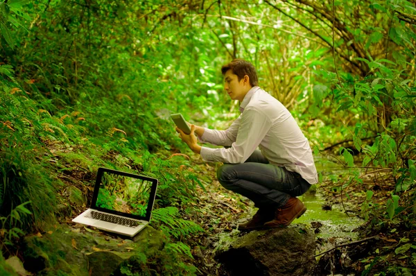 Homem usando tablet e computador pessoal na selva — Fotografia de Stock