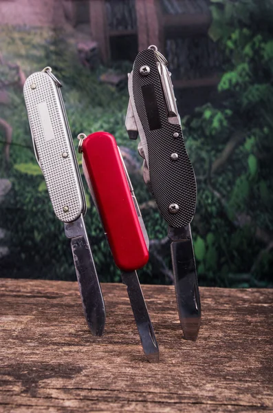 Several swiss army knifes on wood the rainforest — Stock Photo, Image