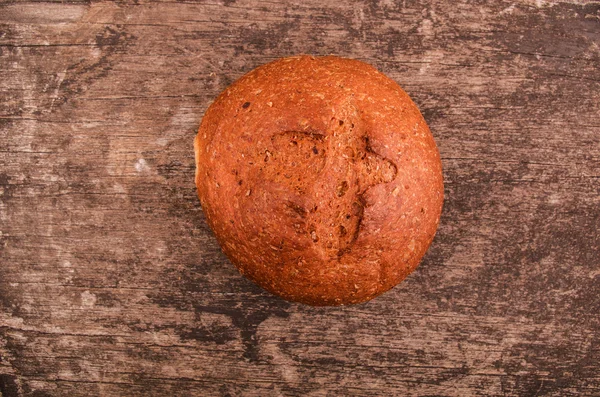 Pão assado fresco de grão inteiro na mesa de madeira — Fotografia de Stock