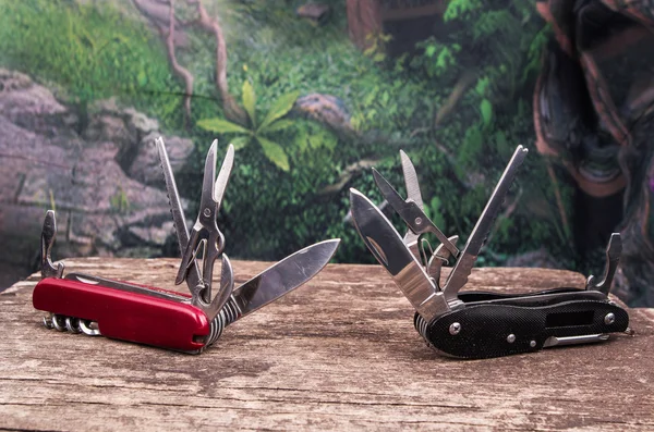 Several swiss army knifes on wood the rainforest — Stock Photo, Image