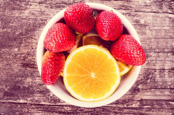 Aardbeien en sinaasappelen op hout — Stockfoto