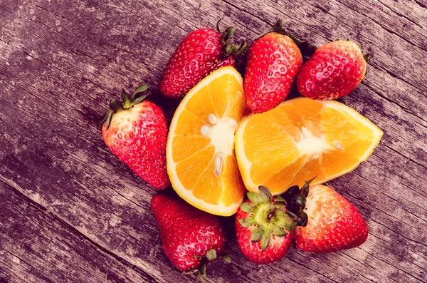 Erdbeeren und Orangen auf Holz — Stockfoto