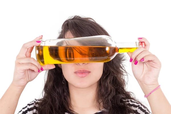 Latin girl hiding eyes behind a yellow bottle — Stock Photo, Image