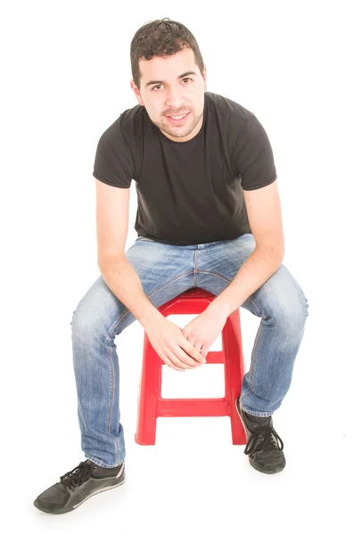 Jeune homme assis sur un tabouret rouge — Photo