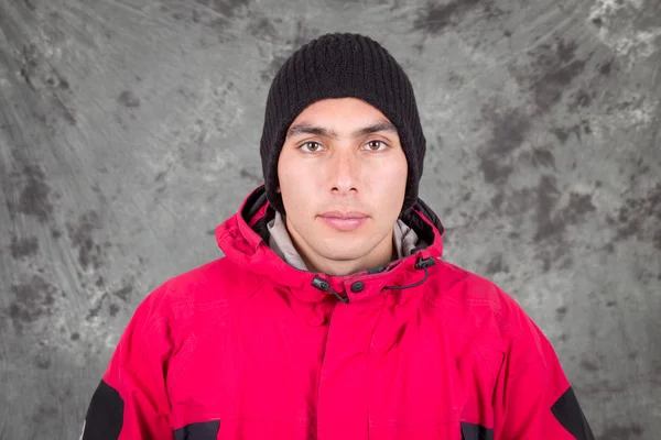 Close-up van jonge knappe man dragen rode jas en zwarte muts over grijze achtergrond — Stockfoto