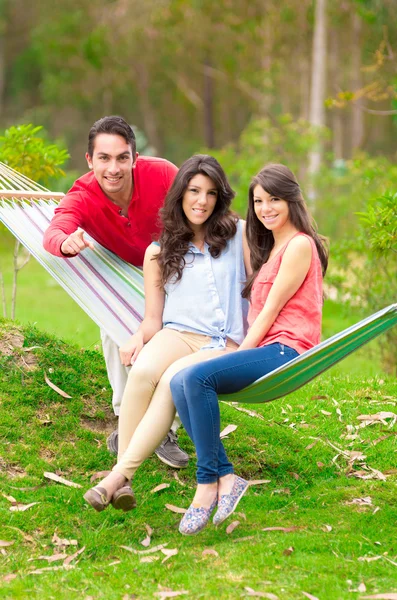 Dos hermosas chicas y un hombre joven en hamaca al aire libre — Foto de Stock
