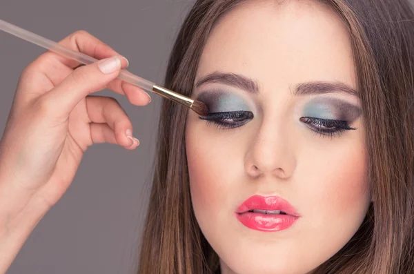 Hermosa joven mujer consiguiendo maquillaje hecho — Foto de Stock