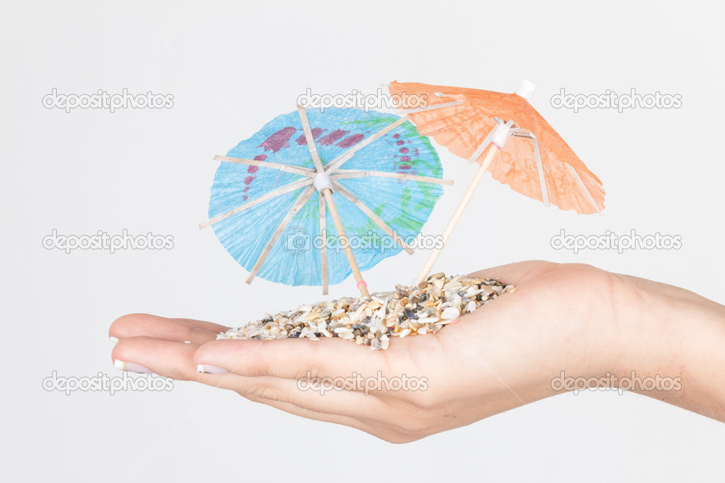 sand on hands with mini umbrellas