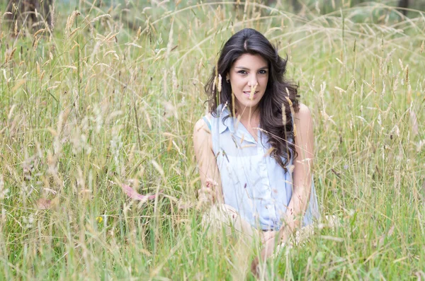 Pretty young girl sitting in a field — Stock Photo, Image