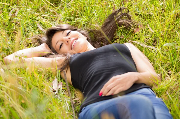 Mooie brunette jonge meisje rustend op groene gras — Stockfoto