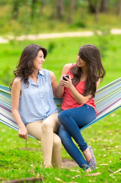 Two young girls resting on a hammock smiling — Stock Photo, Image