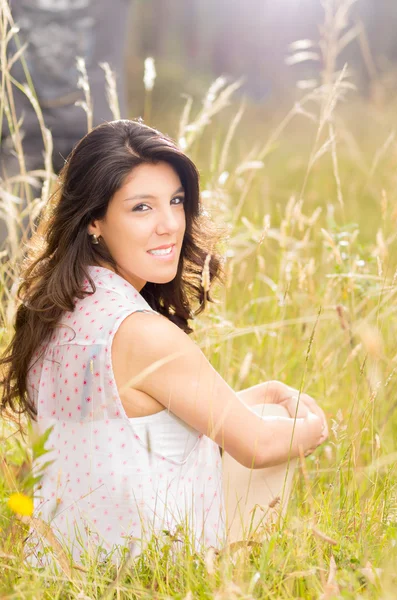 Schöne junge Frau sitzt auf einem Weizenfeld — Stockfoto