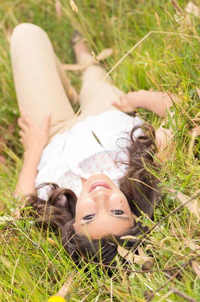 Beautiful young woman lying on green grass — Stock Photo, Image