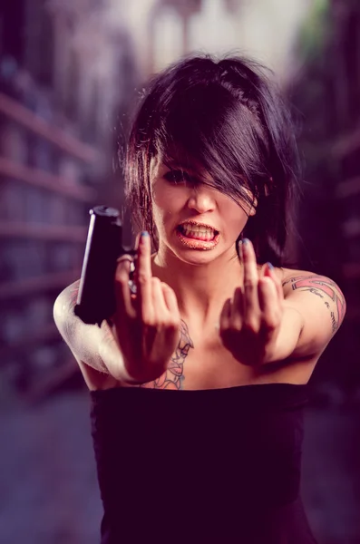 Mooie getatoeëerd meisje met houding bedrijf pistool — Stockfoto