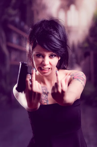 Beautiful tattooed girl with attitude holding gun — Stock Photo, Image