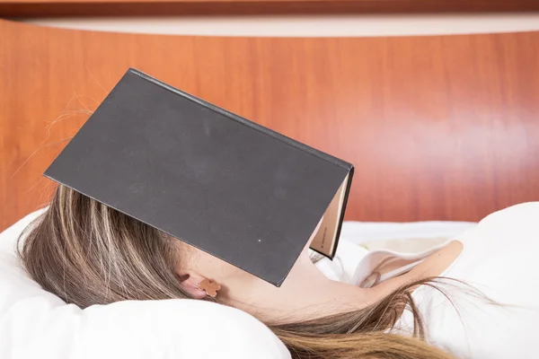 Jong meisje slaapt met boek op haar gezicht — Stockfoto
