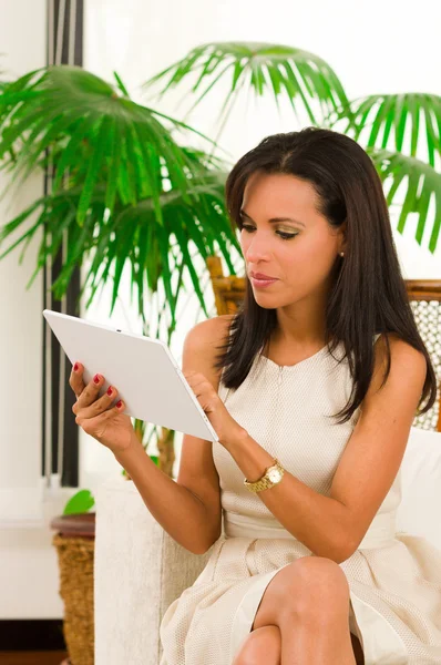 Krásná mladá elegantní žena držící digitální tablet sedí na pohovce — Stock fotografie